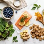 anti-inflammatory diet recipes — colorful spread of omega-3 rich salmon, blueberries, turmeric, leafy greens and walnuts on marble surface