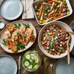 healthy dinner ideas for family , colorful spread of salmon, roasted vegetables, grain salad and water on a wooden family dinner table