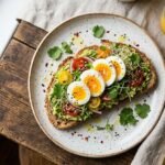 avocado toast toppings overhead shot with poached egg cherry tomatoes microgreens and flaky salt on sourdough