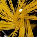 Dry spaghetti fanned across a wide pan of water on the hob, the starting point for how to cook pasta properly