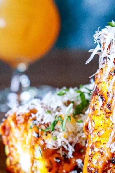 Charred Mexican street corn recipe served on the cob with grated cotija cheese, chile powder and chopped cilantro