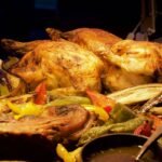 Whole roast chickens resting on a tray of roasted peppers and aubergine with a jug of gravy, a spread of side dishes for roast chicken