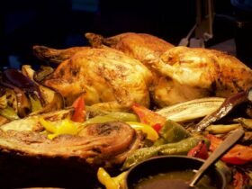 Whole roast chickens resting on a tray of roasted peppers and aubergine with a jug of gravy, a spread of side dishes for roast chicken