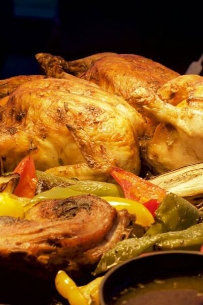 Whole roast chickens resting on a tray of roasted peppers and aubergine with a jug of gravy, a spread of side dishes for roast chicken