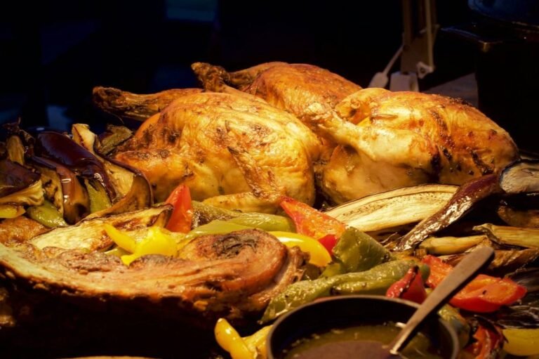 Whole roast chickens resting on a tray of roasted peppers and aubergine with a jug of gravy, a spread of side dishes for roast chicken