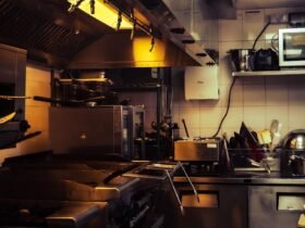Commercial kitchen equipment checklist in practice: range under a Type I hood, prep tables, refrigerated base and a fire extinguisher in a small restaurant kitchen