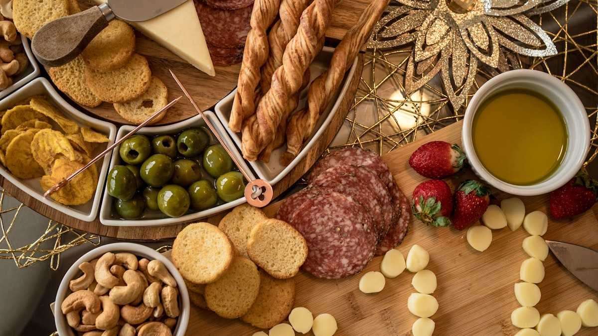 Costco charcuterie board style spread with salami, cheese, olives, nuts, strawberries and crackers on a wooden table