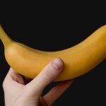 Hand with a sports watch holding a ripe banana, the classic answer to is a banana good before a workout