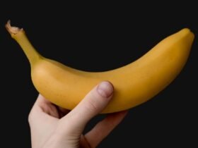 Hand with a sports watch holding a ripe banana, the classic answer to is a banana good before a workout
