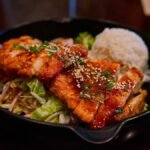 Post workout meal ideas: plate of glazed chicken with white rice and greens in a cast iron skillet