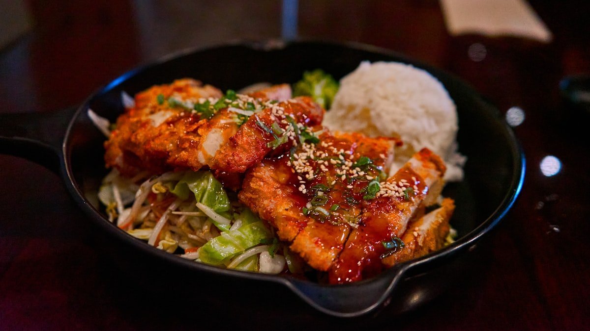 Post workout meal ideas: plate of glazed chicken with white rice and greens in a cast iron skillet