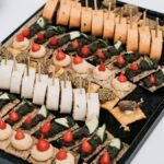 Cocktail party food ideas on one tray: canapes, pinwheels and topped crackers lined up for a standing crowd