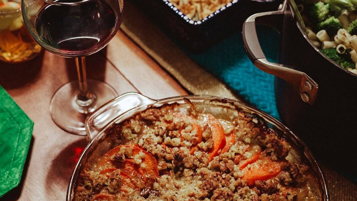 Thanksgiving vegetable side dishes on the table: sweet potato casserole with pecan crumble beside a pot of broccoli