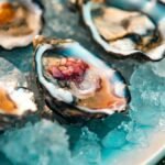Mignonette recipe in action: minced shallot in vinegar spooned onto oysters resting on crushed ice