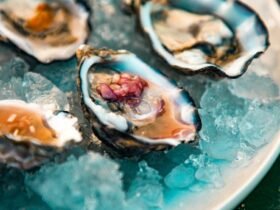 Mignonette recipe in action: minced shallot in vinegar spooned onto oysters resting on crushed ice