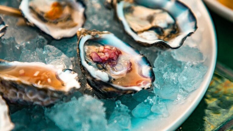 Mignonette recipe in action: minced shallot in vinegar spooned onto oysters resting on crushed ice